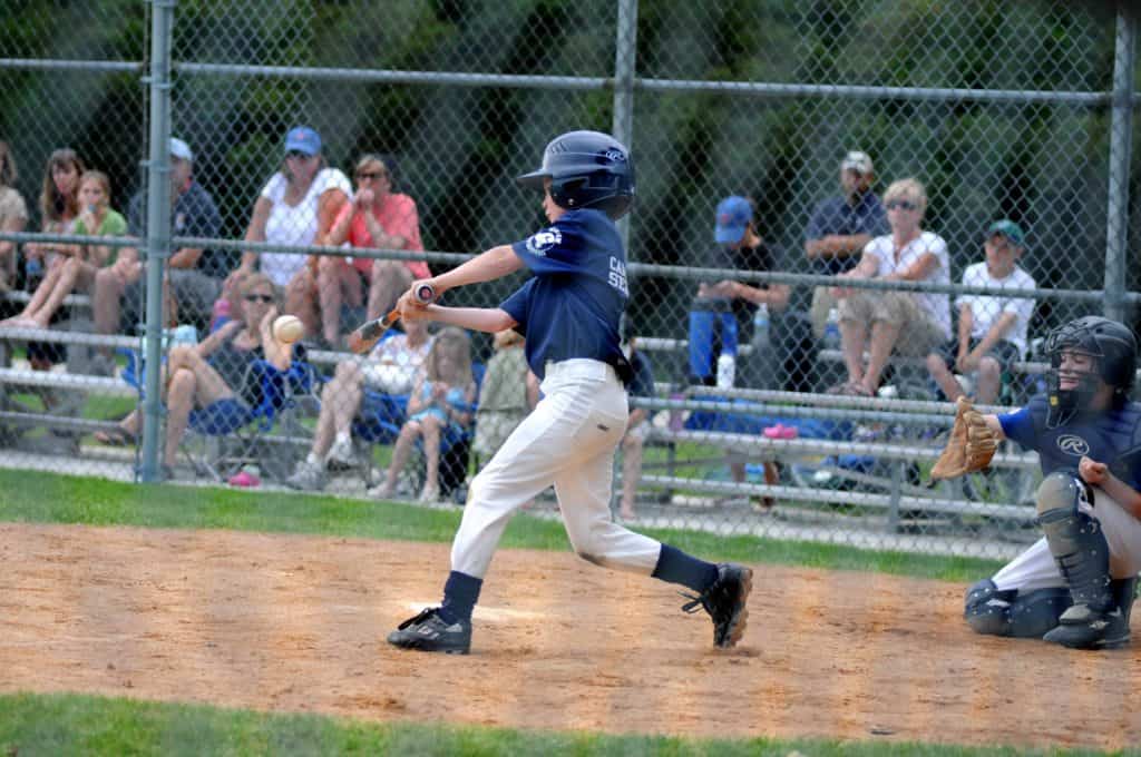 a boy with a baseball bat hits a baseball