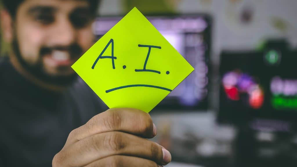 a man holds a post-it note with the letters A.I written on it